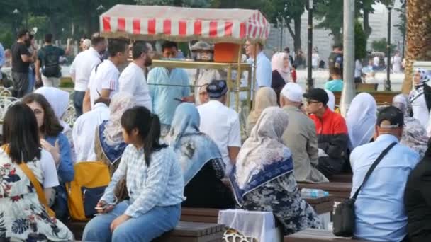 11 juni 2019-Istanbul, Turkiet: muslimska människor, män och kvinnor i särskilda kläder sitter på bänken på torget nära St Sophia — Stockvideo