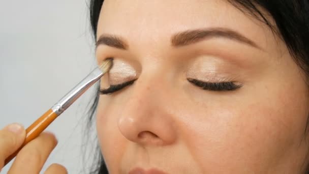 Portrét krásné modrooké ženské modři s dlouhými černými vlasy, které dělají večerní hnědoušový make-up a obočí se speciálním kartáčem — Stock video