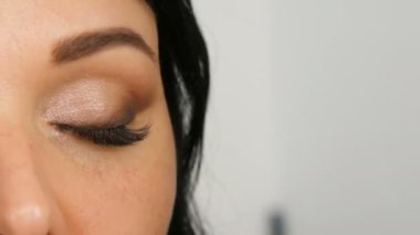 Özel fırça ile akşam kahverengi göz makyajı ve kaş yapıyor uzun siyah saçlı güzel bir mavi gözlü kadın modeli portresi