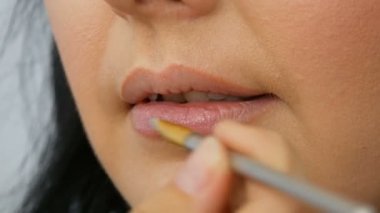 Stilist güzellik salonunda özel bir fırça ile dudakları boyar yakından görünümü