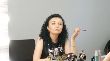 Kıvırcık siyah saçlı güzel genç esmer kadın ayna önünde kendini makyaj yok