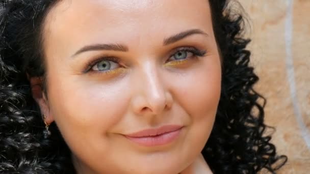 Schöne junge brünette kaukasische Frau mit lockigem schwarzem Haar posiert und lächelt vor der Kamera — Stockvideo