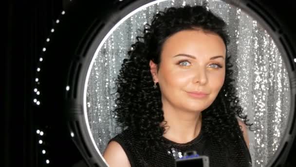 Vacker ung Brunett kaukasiska kvinna med lockigt svart hår poserar och ler framför kameran i studion — Stockvideo