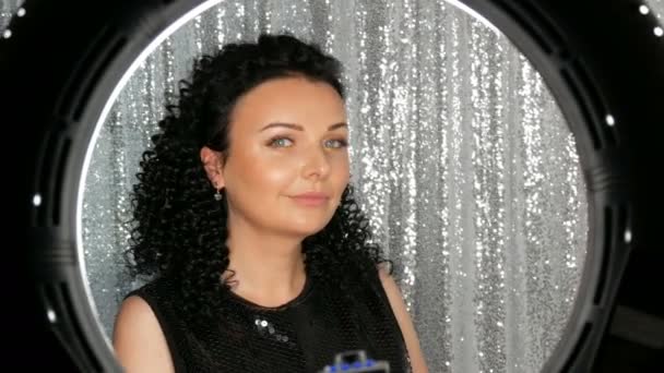 Gyönyörű fiatal barna kaukázusi nő göndör, Fekete hajú pózol, és mosolyogva előtt kamera stúdióban — Stock videók