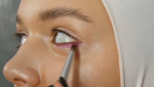 Vrouw make-up Artist stylist maakt make-up modieuze roze rokerige ogen met speciale make-up borstel van jonge model — Stockvideo