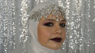 Beyaz bir görüntü ve parlak çok renkli makyaj ile gümüş bir taç modeli yüz dumanlı bir göz olarak adlandırılan, gümüş bir arka plan üzerinde model ajansı kamera önünde poz. Yüksek moda