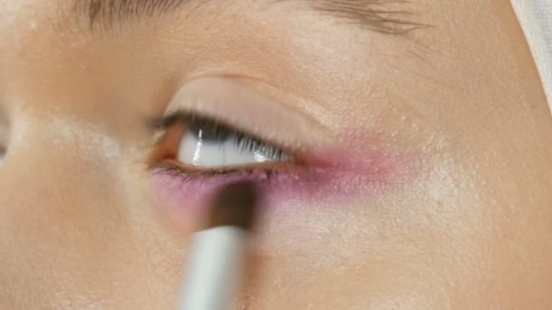 Visagistin Stylistin macht Make-up modisch rosa Smoky Eyes mit speziellem Make-up Pinsel des jungen Modells — Stockvideo