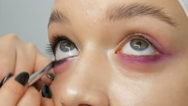 Mujer maquillaje artista estilista hace que el maquillaje de moda rosa ojos ahumados con cepillo de maquillaje especial de modelo joven — Vídeo de stock