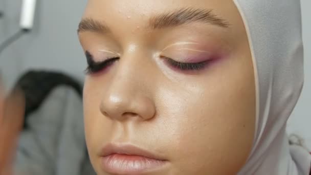 Woman make-up artist stylist makes makeup fashionable pink smoky eyes with special makeup brush of young model — Stock Video