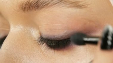 Kadın makyaj sanatçısı stilist genç modelin özel makyaj fırçası ile makyaj moda pembe dumanlı gözler yapar