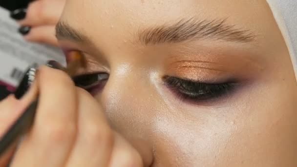 Mujer maquillaje artista estilista hace que el maquillaje de moda rosa ojos ahumados con cepillo de maquillaje especial de modelo joven — Vídeo de stock