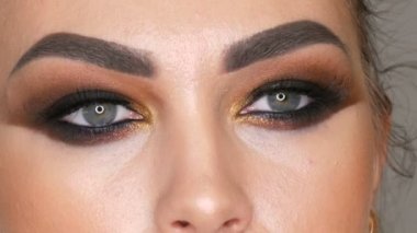 Profesyonel makyöz yakın çekim makyaj dumanlı gözler kahverengi gölge güzel manken, yeşil gözlü yapar