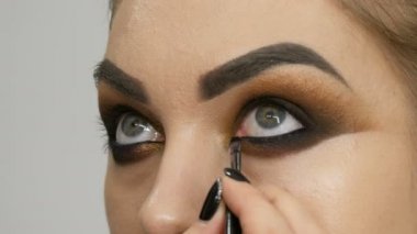 Profesyonel makyöz yakın çekim makyaj dumanlı gözler kahverengi gölge güzel manken, yeşil gözlü yapar