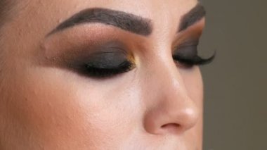 Profesyonel makyöz yakın çekim makyaj dumanlı gözler kahverengi gölge güzel manken, yeşil gözlü yapar
