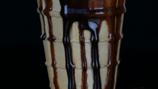 Таяние мороженого, на которое льется шоколадный сироп соус на черном фоне — стоковое видео