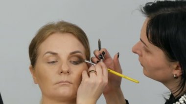 Profesyonel usta makyaj sanatçısı güzellik salonu yakından görünümünde model göz üzerinde özel fırça ile bej göz farı uygular