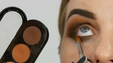 Profesyonel usta makyaj sanatçısı güzellik salonu yakın görünümünde model göz üzerinde özel fırça ile bej göz farı paleti uygular