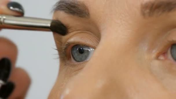 Professionelle Meister Make-up Artist trägt beige Lidschatten mit speziellen Pinsel auf Modell Auge im Schönheitssalon Nahaufnahme — Stockvideo