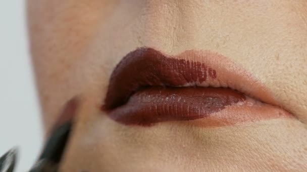 Επαγγελματίας δάσκαλος μακιγιάζ εφαρμόζει σκούρο κόκκινο κραγιόν στο μοντέλο λεπτή χείλη με ειδική βούρτσα και make-up καπνιστή μάτια στο σαλόνι ομορφιάς — Αρχείο Βίντεο