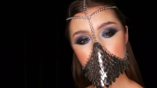 Girl model in unusual iron stylish muzzle. Symbol of the silence of a woman. Sexy tender beautiful young girl model with long hair and blue evening make-up smoky eyes — Stock Video