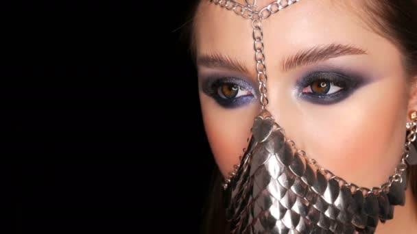 Girl model in unusual iron stylish muzzle. Symbol of the silence of a woman. Sexy tender beautiful young girl model with long hair and blue evening make-up smoky eyes — Stock Video