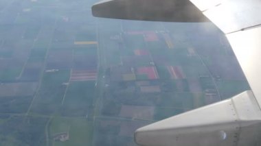 Uçak Hollanda'da çok renkli lale güzel alanları üzerinde uçar, porthole görünümü. Hollanda'nın lale tarlaları üzerinde uçuş uçak kanadı