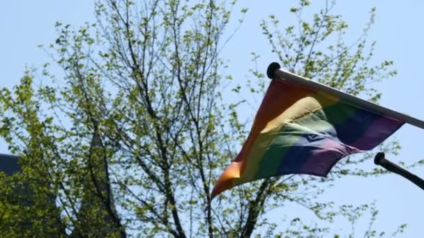Bandera arco iris orgullo gay LGBT volando. Una bandera arco iris multicolor, un símbolo de tráfico no convencional, se balancea en el viento en la capital de los Países Bajos, Amsterdam — Vídeo de stock