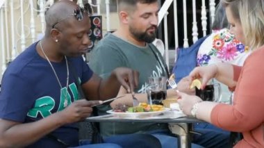 Amsterdam, Hollanda - 21 Nisan 2019: Çeşitli milletlerden şişman insanlar açık hava restoranında et, patates ve sebzeli büyük porsiyonet yiyor. Aşırı kilolu, yetersiz beslenme sorunları
