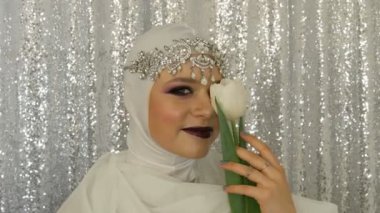 Beyaz bir görüntü ve parlak çok renkli makyaj ile gümüş bir taç model ve lale yüzü dumanlı bir göz olarak adlandırılan, gümüş bir arka plan üzerinde model ajansı kamera önünde poz. Yüksek moda