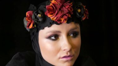 Güzel makyaj ile profesyonel kız modeli siyah kap ve çelenk başında bir karadul görüntüdeki siyah arka plan üzerine kamera önünde poz veriyor. Yüksek moda