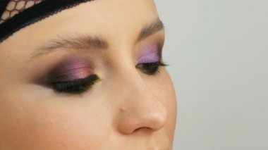 Profesyonel makyaj sanatçısı göz makyajı modeli yapar. Akşam makyajlı yüz modeli. Yakından bak.