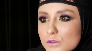 Güzel makyaj ile profesyonel kız modeli siyah dul görüntüsünde siyah arka planda kameranın önünde kafasına siyah bir kap içinde pozlar. Yüksek moda