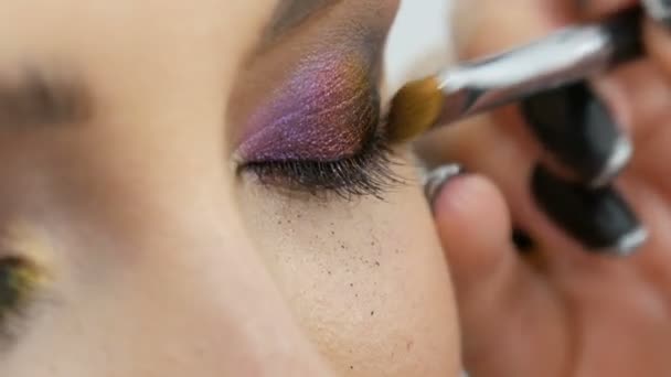 Fashionabla flerfärgad ögonskugga kameleont med gul lila grå silver färg på ögonlocket av vacker flicka modell med bruna ögon. Professionell kosmetisk makeup. Öga på nära håll se — Stockvideo