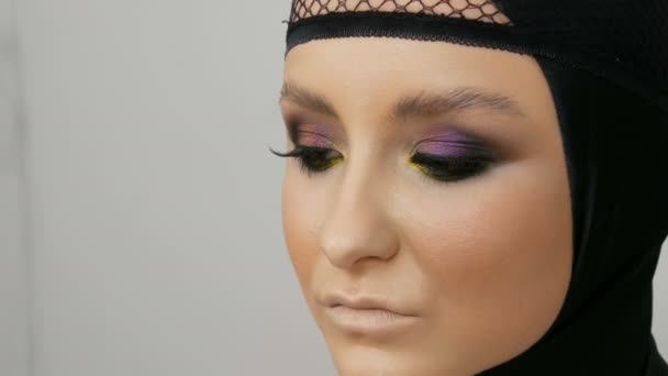 Професійна дівчина-модель з красивими позуваннями макіяжу в чорній шапці на голові на зображенні чорної вдови. Високомодні — стокове відео