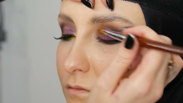 Fashionable multi-colored eye shadow chameleon with yellow purple gray silver color on the eyelid of beautiful girl model with brown eyes. Professional cosmetic makeup. Eye close up view — Stock Video