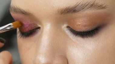 Yüksek moda. Makyaj sanatçısı stüdyoda çekim için kız modeli için pembe ve siyah renk profesyonel makyaj dumanlı gözleri yapma. Yeşil göz modelinin yakından görünümü