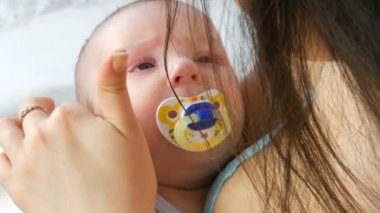 Güzel bir genç uzun saçlı anne hafifçe dokunur ve yeni doğan bebeğini kollarında yatağında otururken beşik. Childs'ın yüz görünümü kapatın