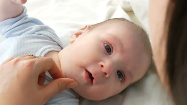 Anne, yatağında otururken yeni doğan bebeğine hafifçe dokunur ve kollarına belini sıkıyor. Çocuklar yakından görünüme sahip — Stok video