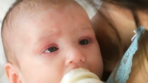 Een twee maanden durende pasgeboren baby ligt aan de armen van de moeder en een tepel zuigt uit fles melk — Stockvideo