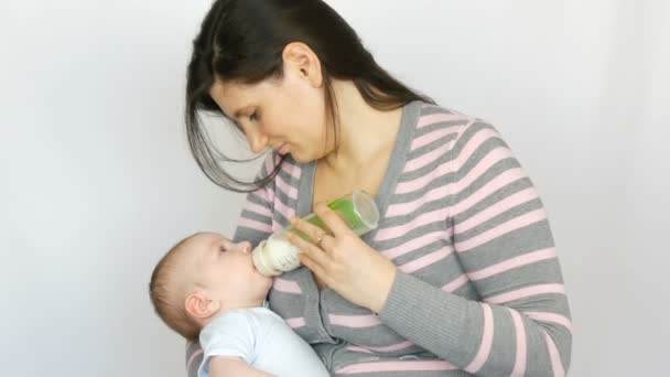 Fiatal szép anya, hosszú, Sötét haja van egy újszülött csecsemő baba két hónapos fehér háttér stúdióban — Stock videók
