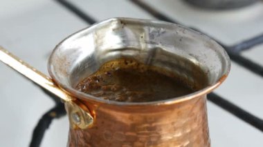 Bakır bir Türk'te çekilmiş siyah kahve demlenir ve gaz sobasında kaynatılır. Barista evde sıcak lezzetli içecek hazırlanıyor