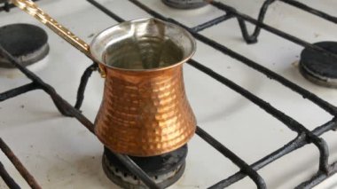 Çay kaşığı beyaz gaz sobası üzerinde duran bir bakır Türk siyah çekilmiş kahve koyar