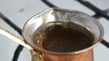 Bakır bir Türk'te çekilmiş siyah kahve demlenir ve gaz sobasında kaynatılır. Barista evde sıcak lezzetli içecek hazırlarken yakın