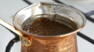 Bakır bir Türk'te çekilmiş siyah kahve demlenir ve gaz sobasında kaynatılır. Barista evde sıcak lezzetli içecek hazırlarken yakın
