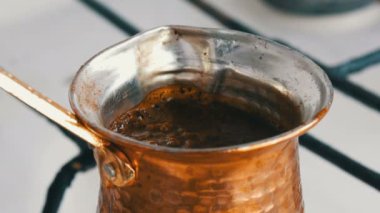 Bakır bir Türk'te çekilmiş siyah kahve demlenir ve gaz sobasında kaynatılır. Barista evde sıcak lezzetli içecek hazırlarken yakın