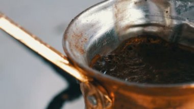 Bakır bir Türk'te çekilmiş siyah kahve demlenir ve gaz sobasında kaynatılır. Barista evde sıcak lezzetli içecek hazırlarken yakın