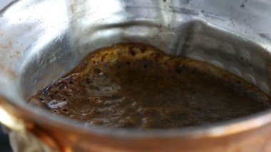 Bakır bir Türk'te çekilmiş siyah kahve demlenir ve gaz sobasında kaynatılır. Barista evde sıcak lezzetli içecek hazırlarken yakın