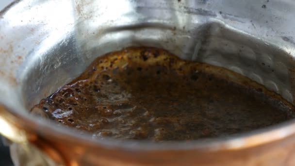 O café preto de terra em um turco de cobre é fabricado e ferve em um fogão a gás. Barista preparar bebida saborosa quente em casa close-up — Vídeo de Stock