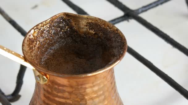 Abgekochter, gemahlener schwarzer Kaffee in einem Kupfertürken auf weißem Gasherd — Stockvideo