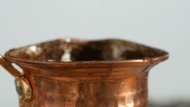 Abgekochter, gemahlener schwarzer Kaffee in einem Kupfertürken auf weißem Gasherd Nahaufnahme — Stockvideo